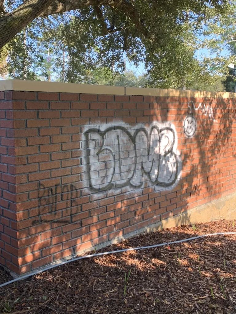 Brick wall covered in graffiti before cleaning