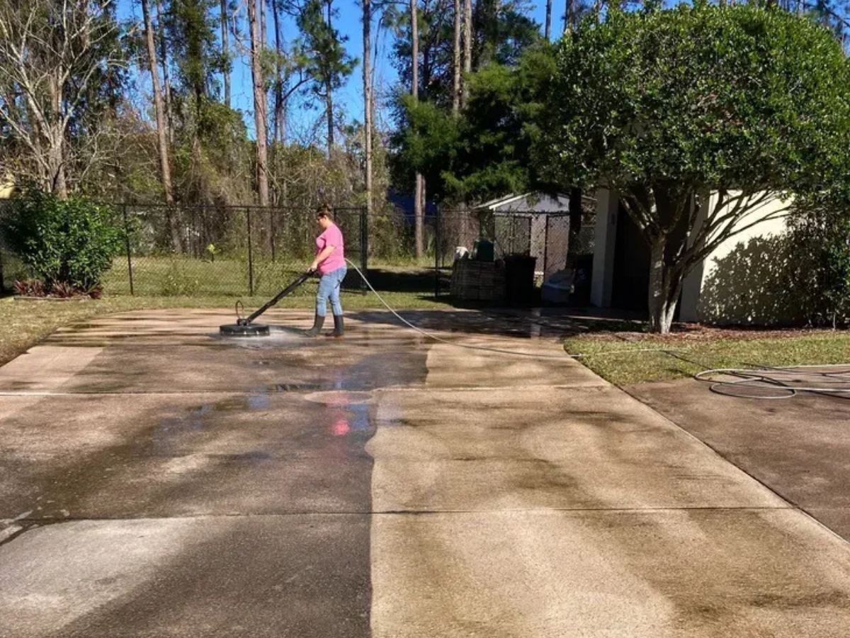 Wright's crew member pressure washing a concrete driveway